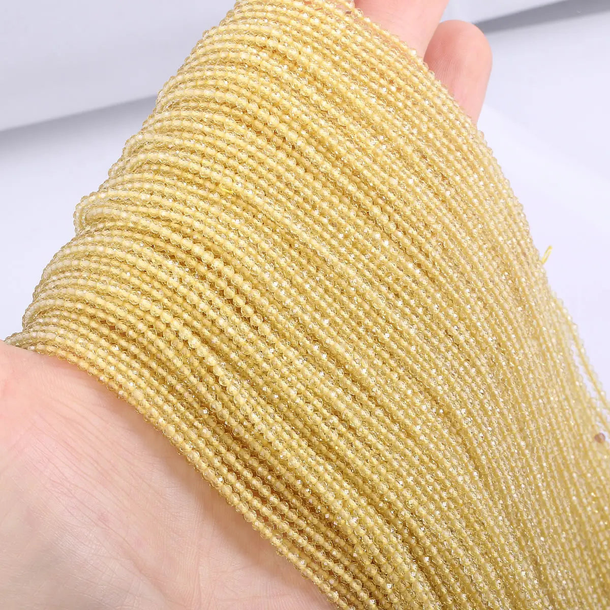 A hand holds a strand of faceted natural stone beads used for DIY jewelry making