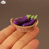 A hand holds a woven basket filled with purple and green miniature bell peppers.