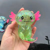 A hand holds a translucent, glittery green axolotl stress relief toy with pink fins and eyes.