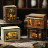 A wooden miniature dollhouse kit featuring a detailed Victorian-style shop facade with glass windows and interior lighting.