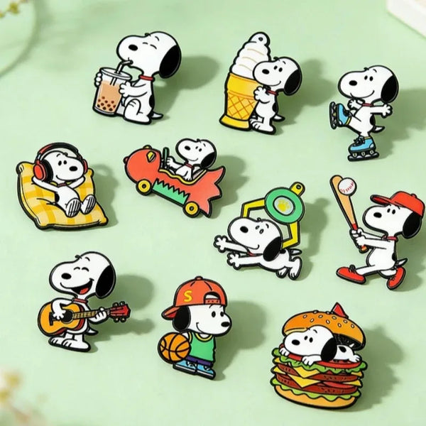 A set of seven enamel pins featuring Snoopy and other cartoon characters in various poses