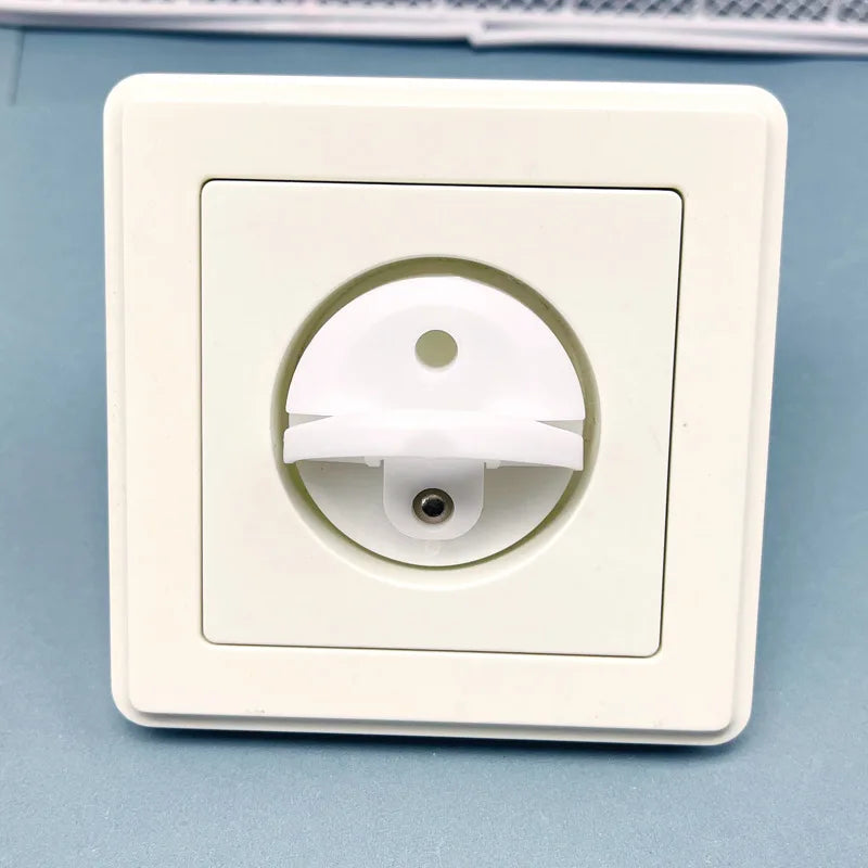 A white rotating socket safety cover for baby proofing is shown in a square plastic housing.