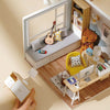 A DIY wooden miniature dollhouse kit is displayed on a wooden shelf next to a window frame.