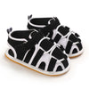 A pair of black and white breathable baby first walker sandals with a soft anti-slip sole.