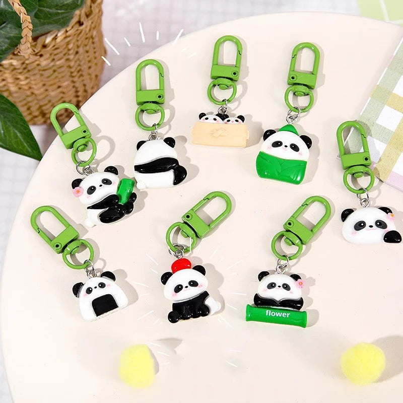 A collection of adorable panda keychains with green clasps displayed on a white plate.