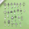 A collection of vintage key charms and pendants in silver metal on a light green background.
