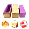 A set of purple rectangular silicone soap molds with wooden casings and a cutting knife.