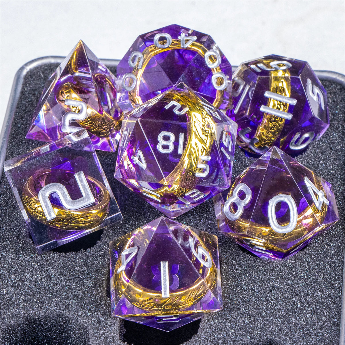 A set of translucent purple resin dice with golden elven numbers, arranged on a dark surface.