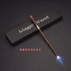 A dark wooden magic wand with an LED light at the tip is displayed on a black surface.