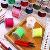 A collection of various colored nylon knotting cord and embroidery thread spools on a wooden tray with pliers and a ruler.