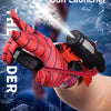 A hand wearing a red Spider-themed glove is launching a water stream from a black and orange wrist launcher.