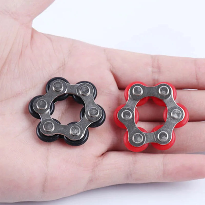 A hand holds two fidget toys, one silver and one red, shaped like interlocking rings.