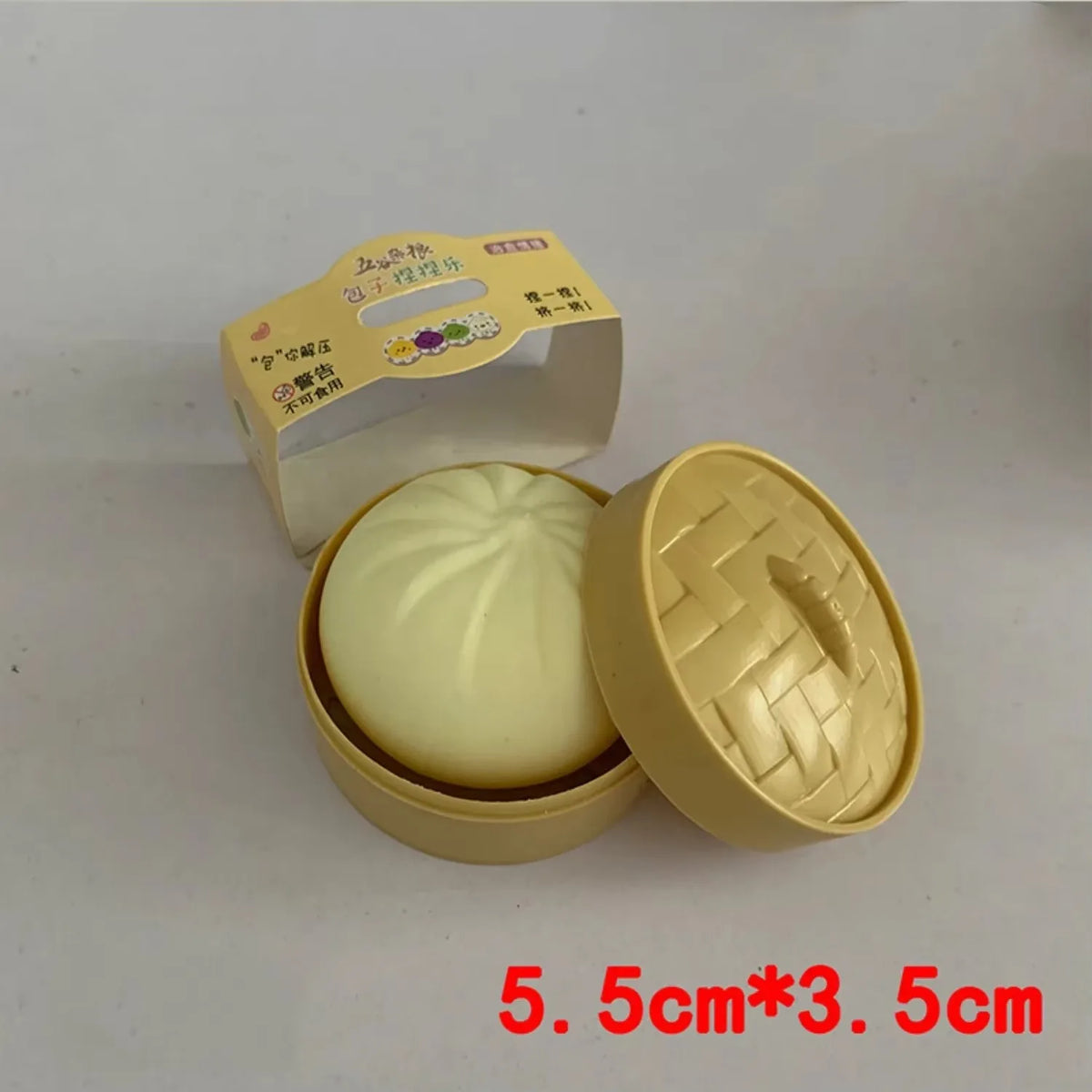 A light yellow dumpling squishy stress ball is shown in an open cardboard container.