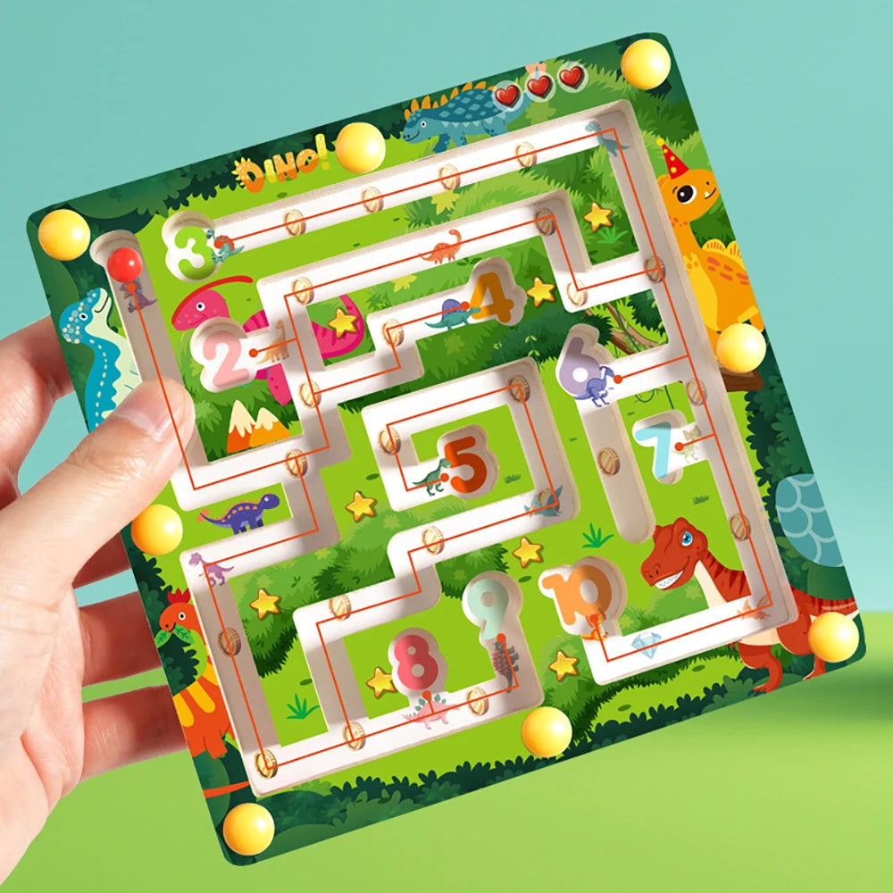 A hand holds a magnetic color and number maze board featuring dinosaurs and counting numbers in a green landscape.
