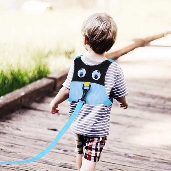 A young child wearing a blue safety harness and leash is running outdoors on a wooden path.
