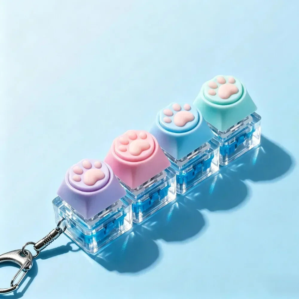 A set of light-up silicone paw print keycaps arranged in a row on a clear plastic keychain.