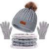A set of women's knit winter hat, scarf, and gloves in gray with a faux fur pom.