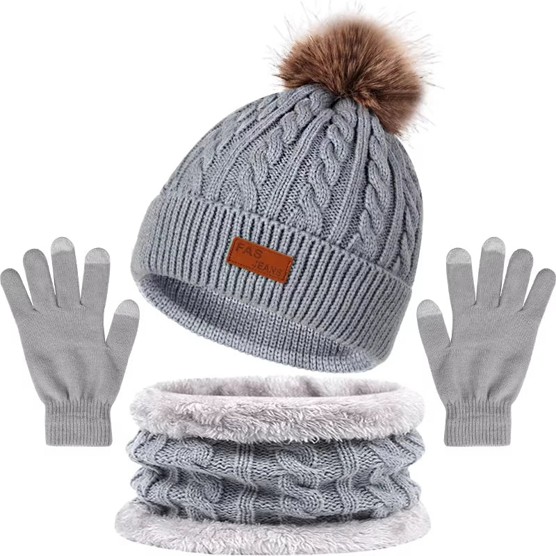 A set of women's knit winter hat, scarf, and gloves in gray with a faux fur pom.
