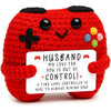 Red crochet ghost doll with black eyes and colorful dots, holding an emotional support card.