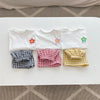 A set of four white girls' summer t-shirts with floral print details laid out on a white surface.