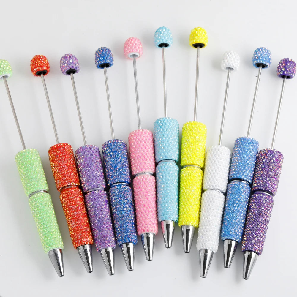A collection of colorful rhinestone pen blanks for DIY jewelry making in various shades of pink, purple, green, and yellow.