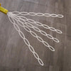 A yellow bubble wand with multiple white, interconnected strands is shown against a wooden floor.