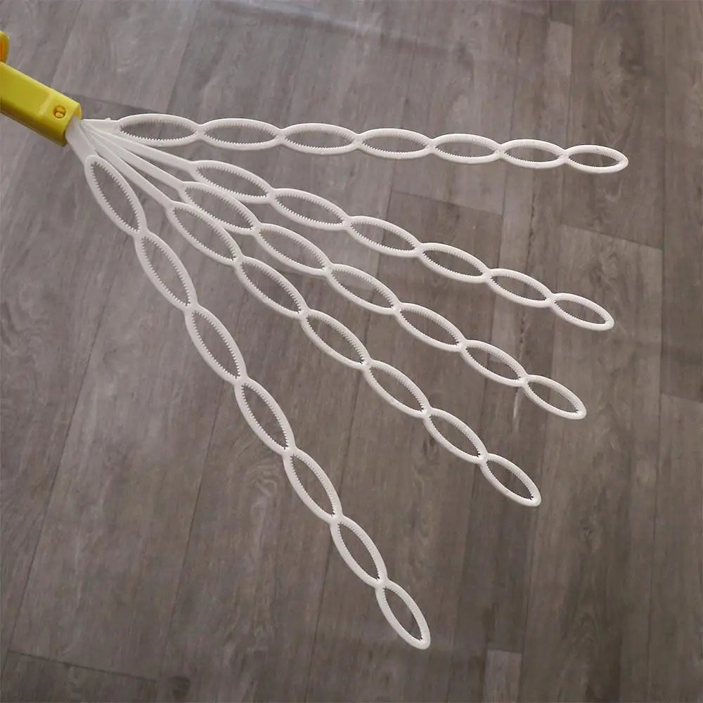 A yellow bubble wand with multiple white, interconnected strands is shown against a wooden floor.
