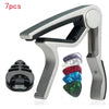 A silver guitar capo holder is shown with seven colored picks and a black pick holder.