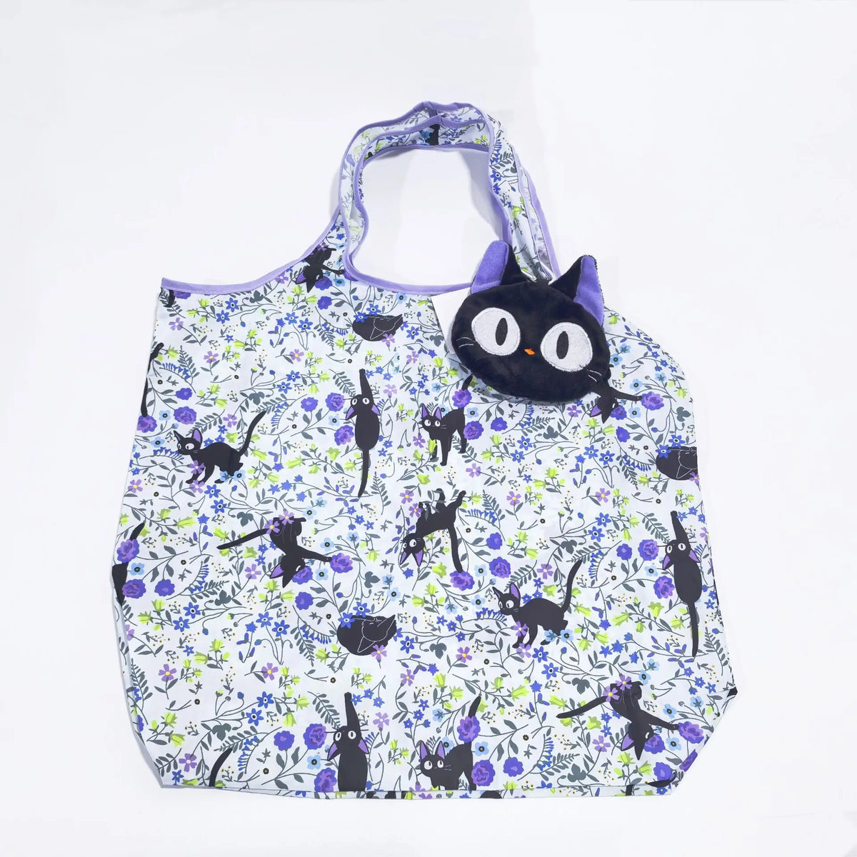 A white fabric tote bag featuring a pattern of black cats and purple flowers.