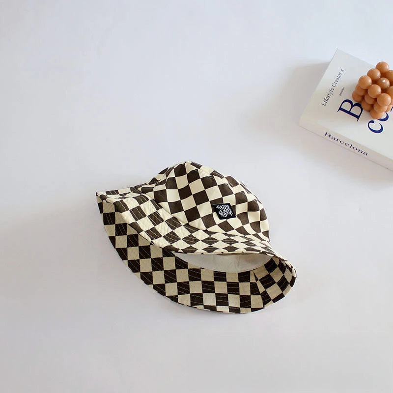 A black and beige checkerboard bucket hat is displayed on a white surface.