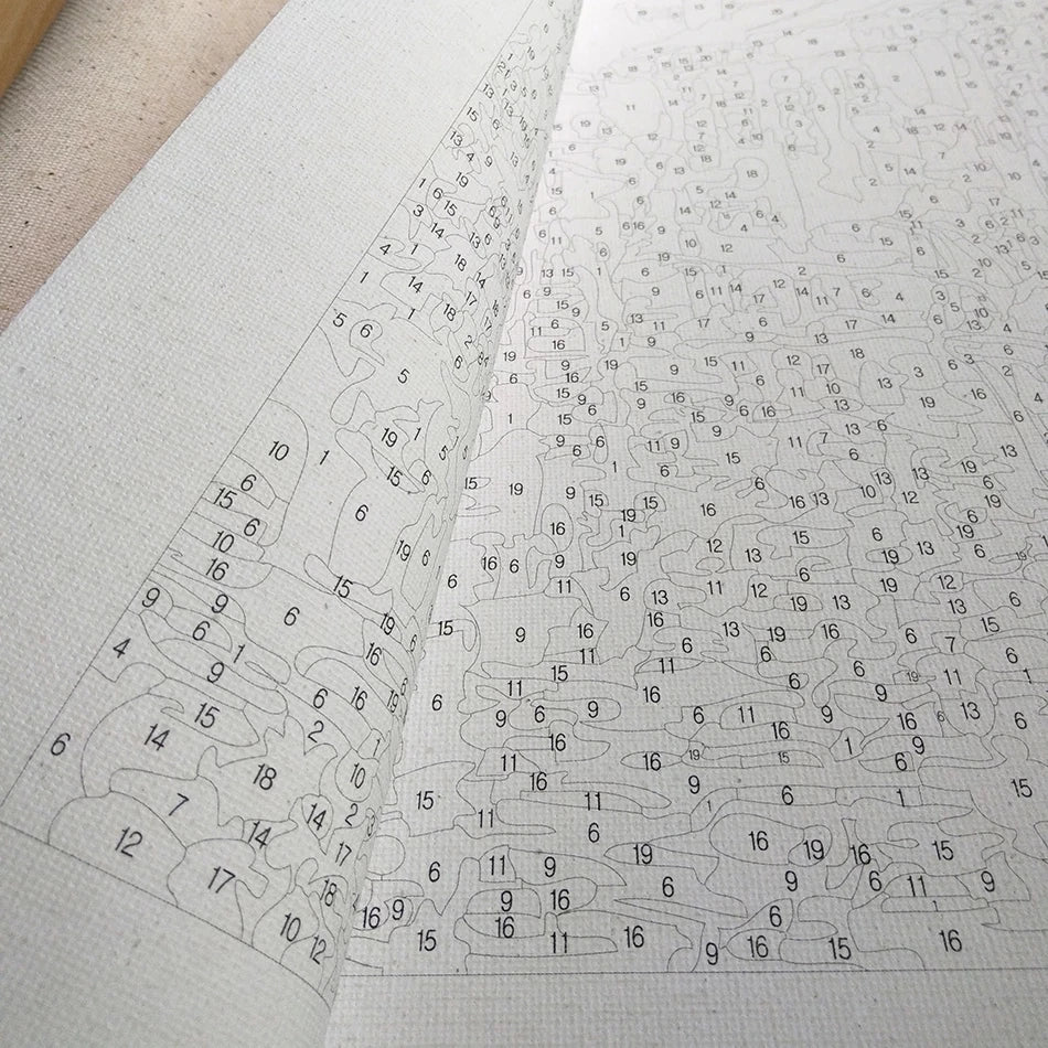 A close-up view of a DIY paint by numbers kit showing a purple landscape design on canvas.