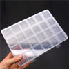 A clear plastic storage box with multiple dividers for organizing jewelry and craft supplies being held in a hand.
