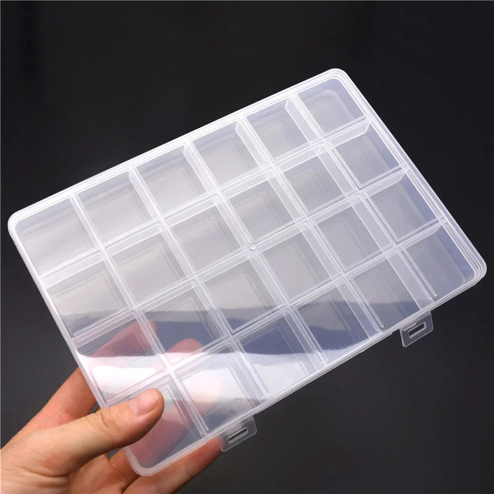 A clear plastic storage box with multiple dividers for organizing jewelry and craft supplies being held in a hand.