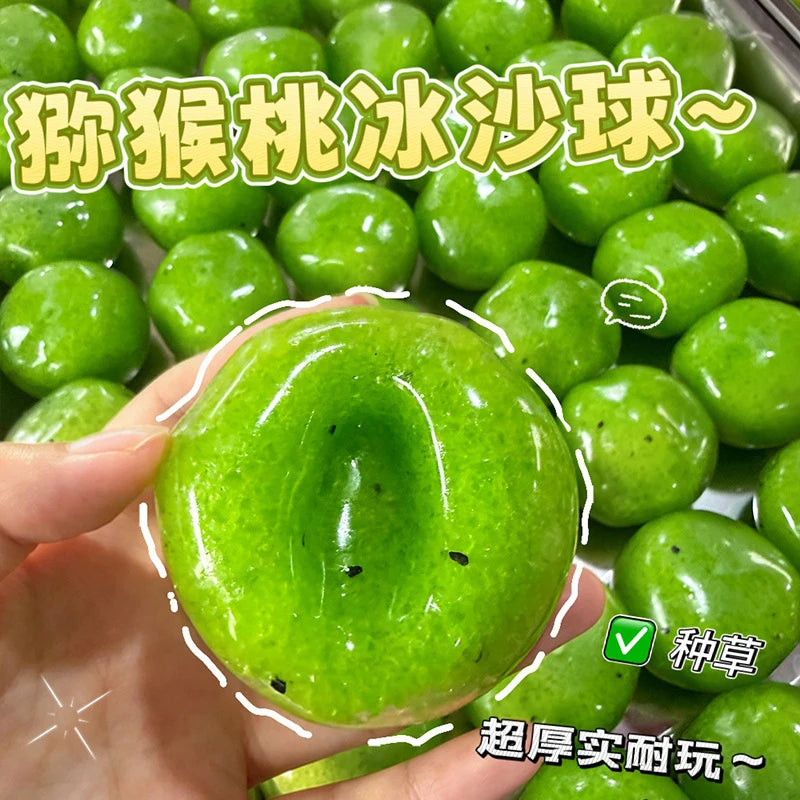 A hand holds a bright green watermelon kiwi squishy stress ball fidget toy with a clear background.