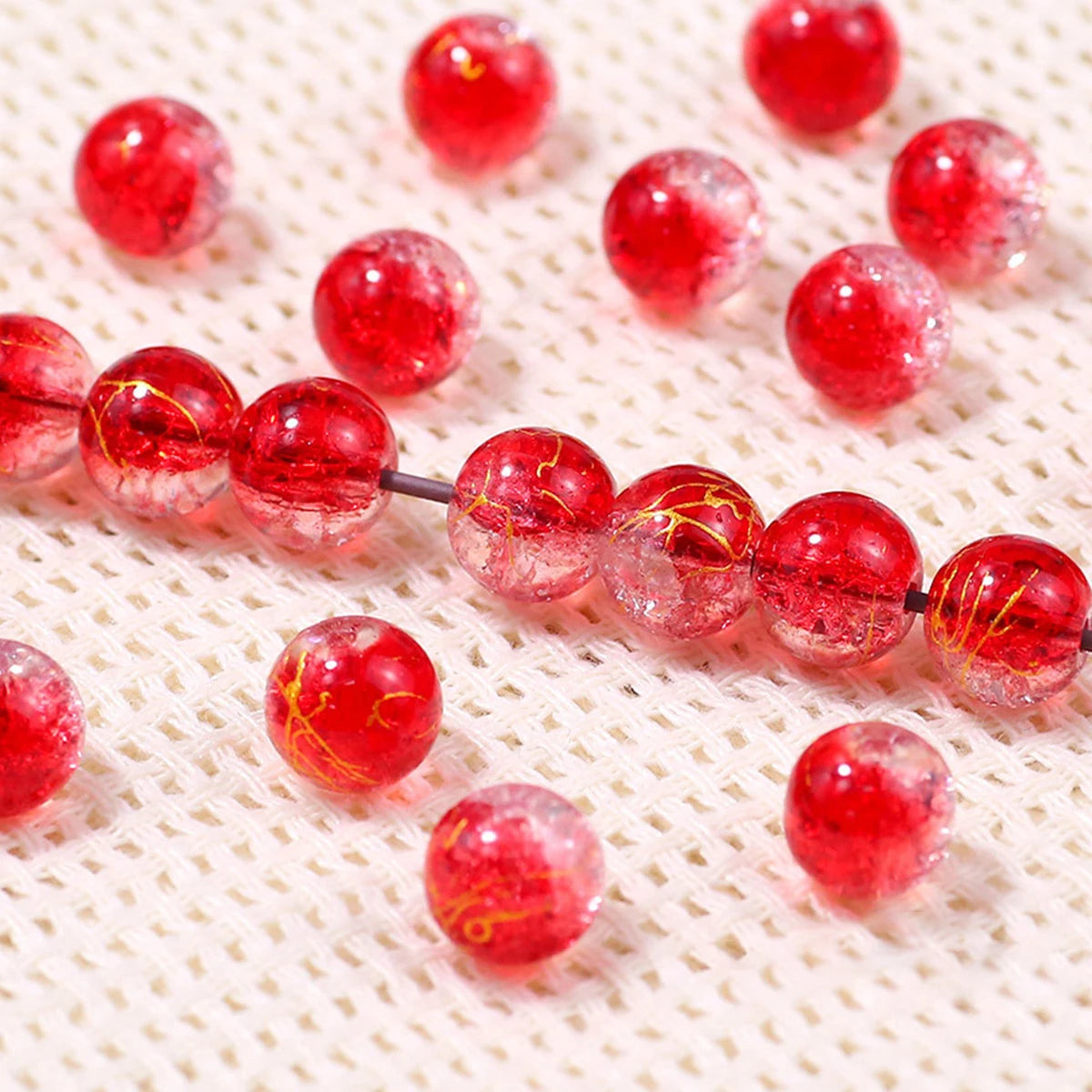 Red gradient crystal glass beads with a golden crackle finish scattered on a white surface