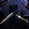 A close-up of a black instrument cable with a gold connector, being handled by a musician in a dark setting.