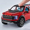 A red 1:20 scale Ford Raptor F150 diecast model truck with lights and sound effects being held by a hand.