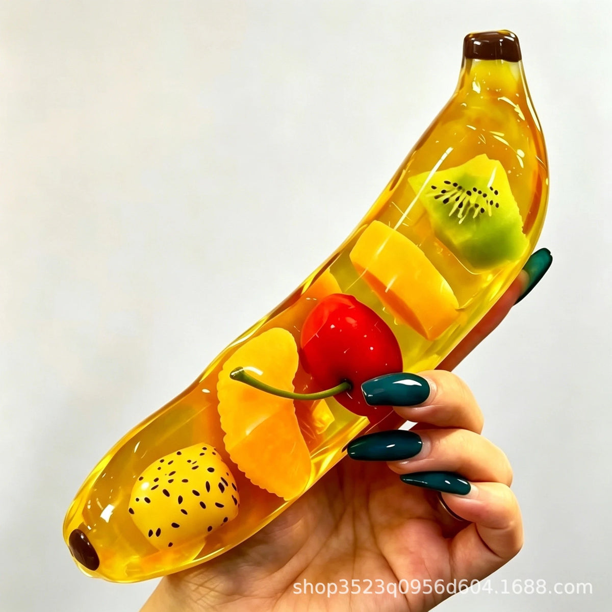 A hand holds a yellow squishy toy shaped like a banana, filled with colorful fruit pieces.