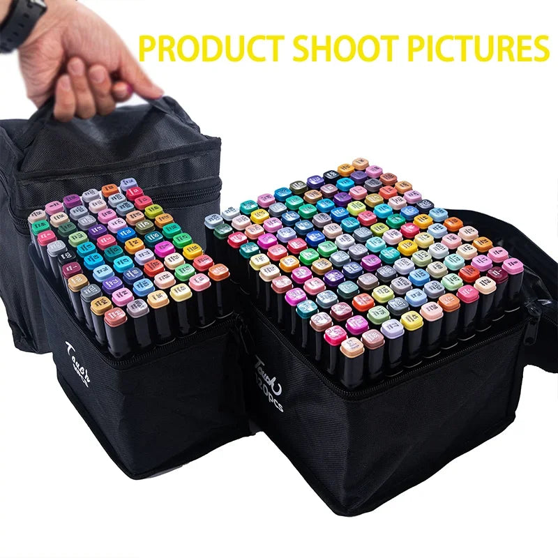 A hand is holding a black pouch containing a large set of colorful dual-tip alcohol art markers for sketching and manga.