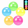 A collection of brightly colored glow-in-the-dark squishy stress balls in green, blue, yellow, and pink.
