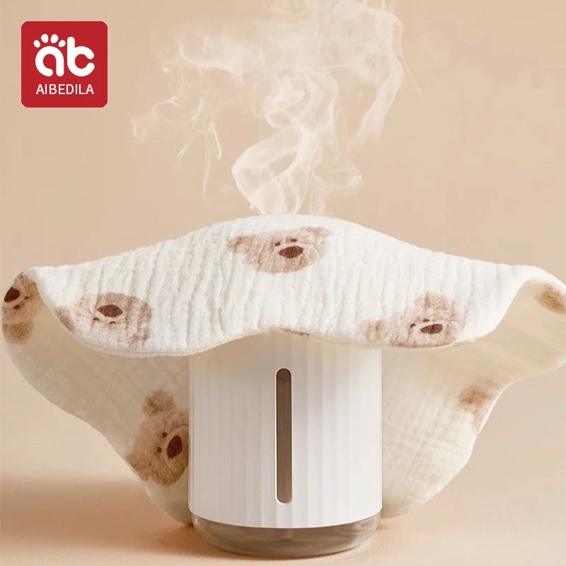A white baby bandana bib is shown emitting steam, resting on a light beige background.
