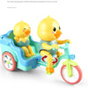 A yellow duck toy is seated on a blue electric tricycle with a green frame.