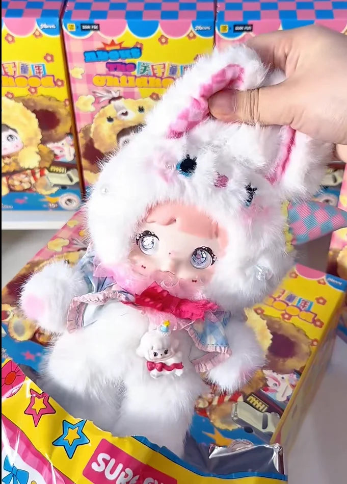 A white fluffy collectible doll with pink accents and a small white figure inside its packaging box.