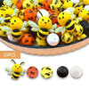 A bowl filled with colorful 3D bee silicone beads in yellow, orange, and white for DIY crafts.