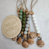 A string of natural wooden beads and silicone clips used as a pacifier or teether.
