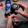 A hand holds a black RC throttle and steering wheel for a full-proportional control system.