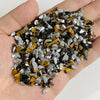 A handful of natural tumbled stone chips featuring mixed colors including black, gray, and golden brown stones.