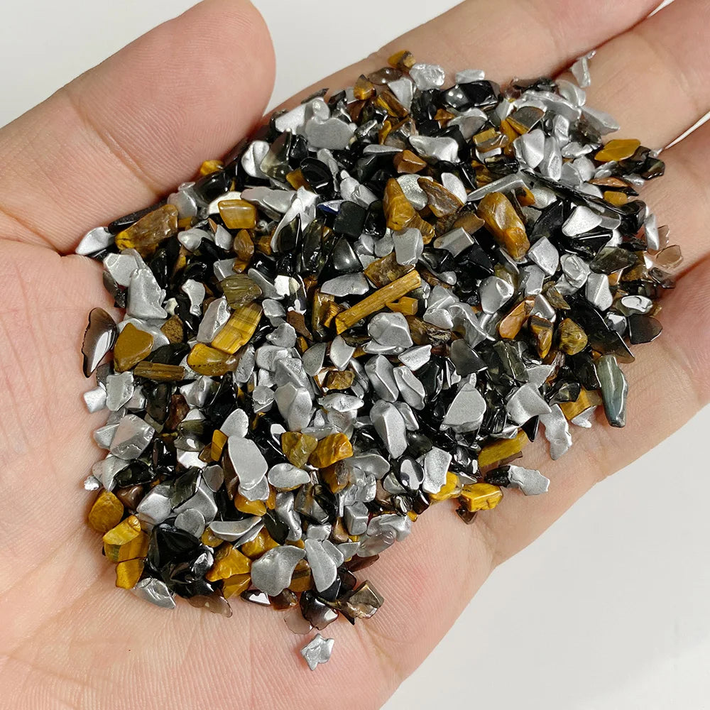 A handful of natural tumbled stone chips featuring mixed colors including black, gray, and golden brown stones.