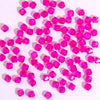 A pile of small, faceted pink crystal bicone glass beads for jewelry making.