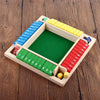 A wooden shut the box dice game set with colored dice and a green board on a wooden surface.